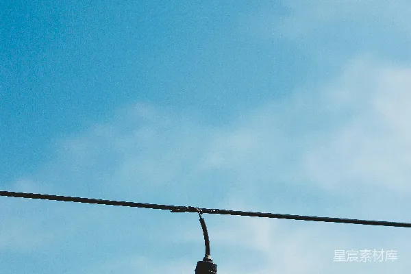 高清摄影 白炽灯泡悬挂在蓝色天空下的黑色电线下方，白天时分。