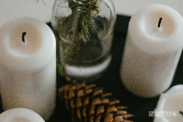 高清摄影 白色的柱形蜡烛旁边有一个棕色的松果。