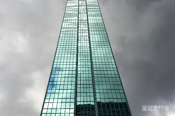 高清摄影 一座非常高大的玻璃建筑，背景是多云的天空。