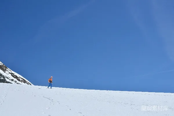 高清摄影 在晴朗的蓝天底下，一个人在雪地里行走。