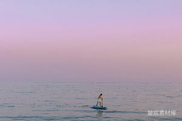 高清摄影 一个人站在冲浪板上，漂浮在大海中央。