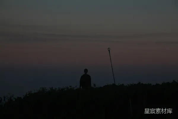 高清摄影 一个男人站在山丘上，旁边有一盏路灯。