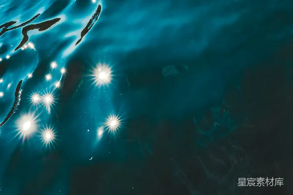 高清摄影 闪烁的蓝色液体表面带有明亮、星星状的反射。
