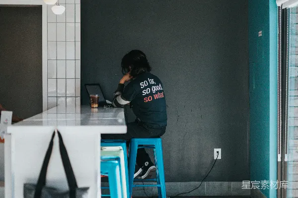 高清摄影 穿着黑色连帽衫的男人坐在蓝色的凳子上。