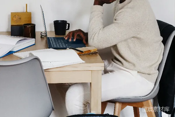 高清摄影 穿白色毛衣的男人坐在椅子上使用微软Surface Laptop 3。