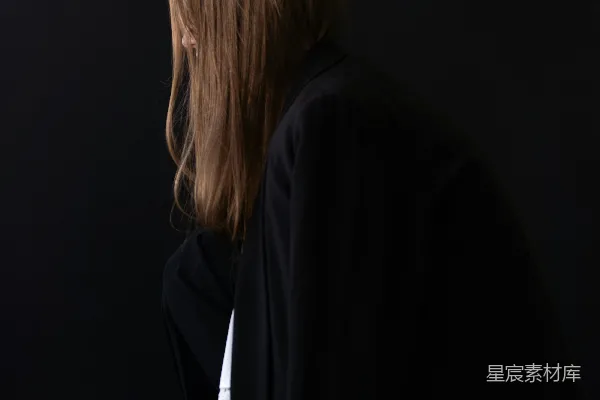 高清摄影 一个女人站在黑暗的房间里，背对着镜头。
