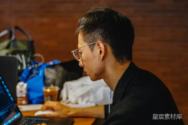 高清摄影 一个人在木制桌子旁使用笔记本电脑工作。
