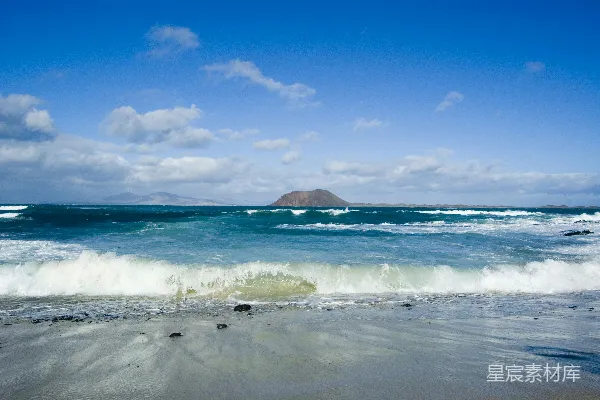 高清摄影 海滩上的波浪与远处的火山