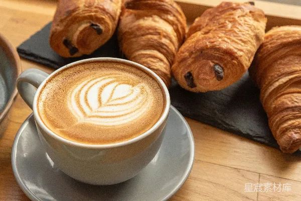 高清摄影 一杯带有拿铁艺术的咖啡和法式羊角面包