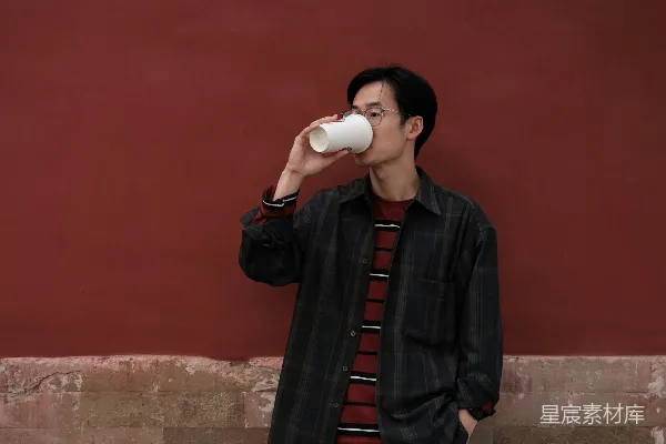 高清摄影 在古墙边悠闲品茶的年轻人