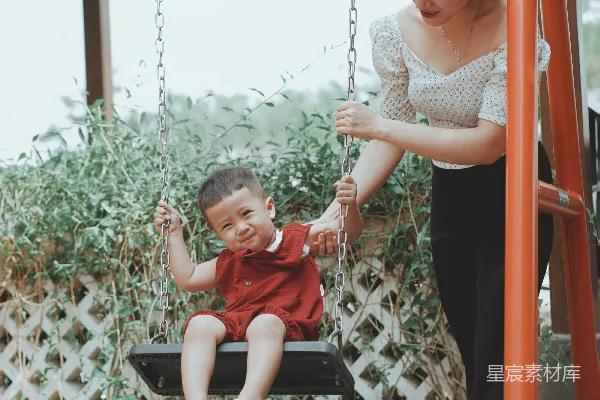 高清摄影 温馨的亲子时光：母亲推着孩子荡秋千