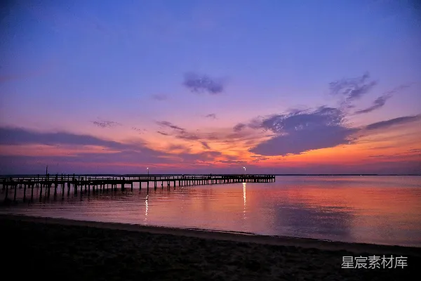 高清摄影 ```json {   title: 黄昏时分的码头与宁静的海滩,   keys: [夕阳, 海滩, 码头, 宁静, 自然美景],   descs: 这张图片展示了黄昏时分的海滩景色。天空被夕阳染成了