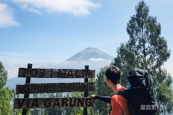 高清摄影 登山者在火山口前的标志旁