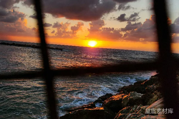 高清摄影 夕阳透过铁窗映照岩石与海浪