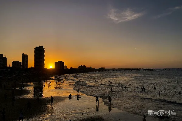 高清摄影 夕阳下的海滩与城市剪影