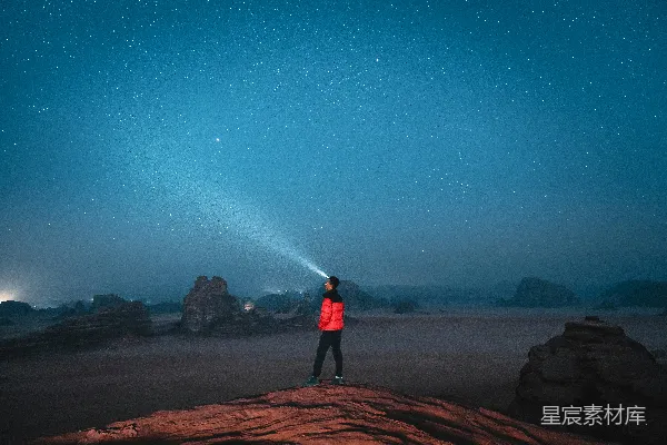 高清摄影 一个人站在岩石上，天空中繁星点点。