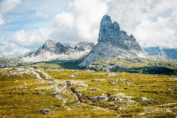 高清摄影 岩石在宽广草地下的日间云层覆盖的蔚蓝天空中形成