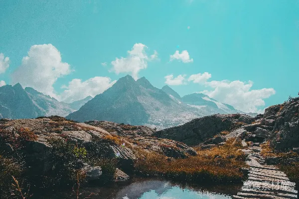 高清摄影 棕色木制码头位于山峦之下靠近湖泊，在蓝天白云的白天阳光下。