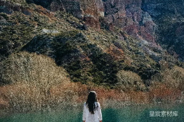 高清摄影 白衣女子站在湖边的棕色岩石结构上，在白天站立。