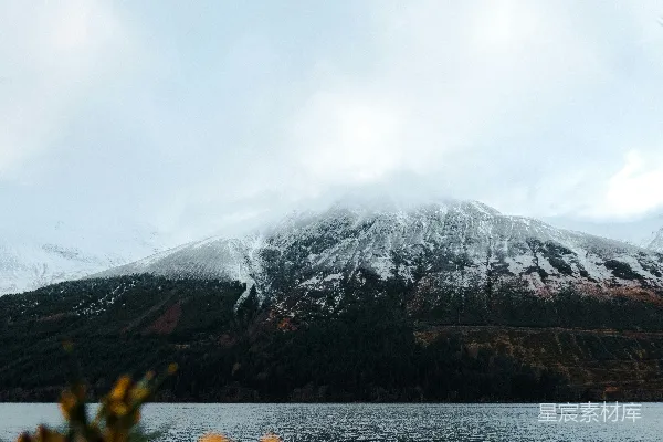 高清摄影 山脚下覆盖着白雪，旁边是一片水域。