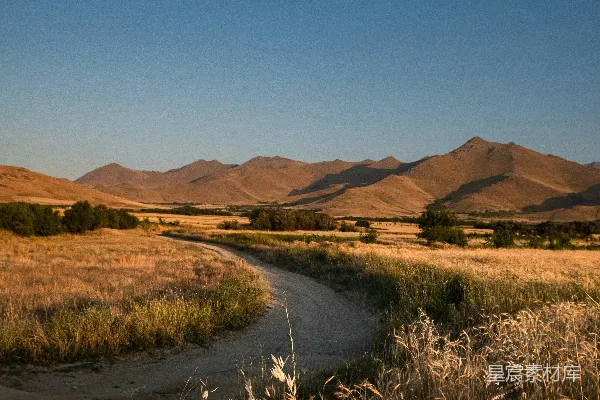 高清摄影 一片开阔的田野，山峰在背景中若隐若现。