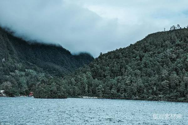 高清摄影 人们乘船在海面上靠近绿山，在白云下度过白天时间