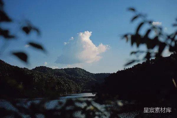 高清摄影 一片云朵漂浮在山坡林间的湖泊之上。