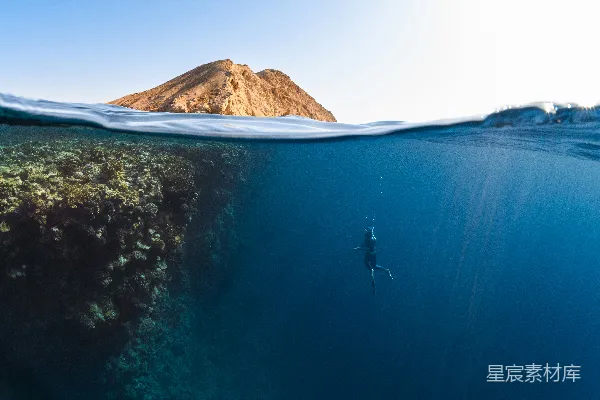 高清摄影 海边一个人在游泳，背景是高山。