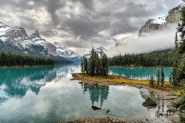 高清摄影 白天山脚下被松树环绕的湖泊周围的雪覆盖着高山
