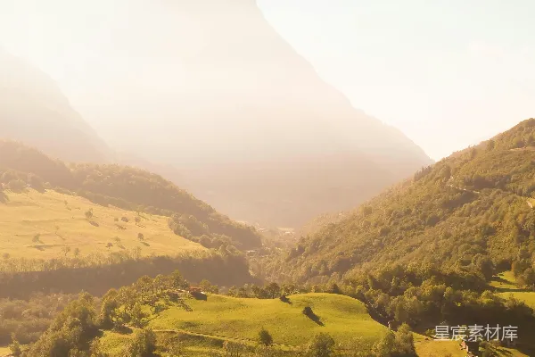 高清摄影 山谷中的美景，远处有房屋和山峦。
