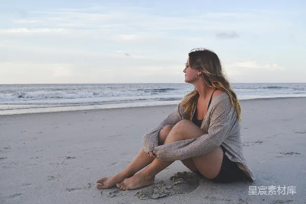 高清摄影 海边上坐着一位妇女，旁边是海洋。